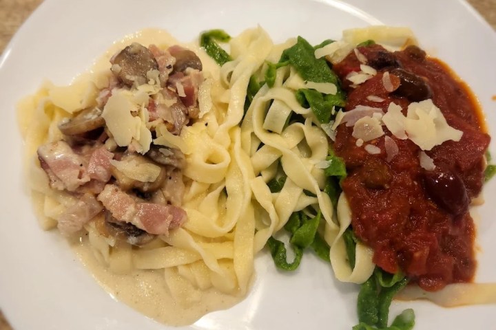 Plate with two types of pasta: creamy mushroom sauce and red tomato sauce with cheese.
