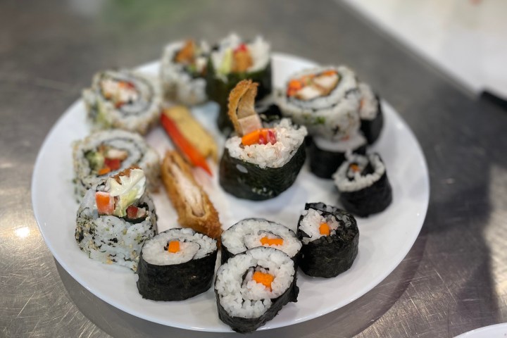 Plate of assorted sushi rolls on a metal surface.