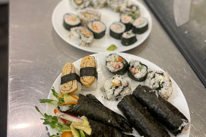 Two plates with assorted sushi rolls on a kitchen counter.