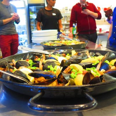 A skillet on a stovetop sizzles a seafood mix