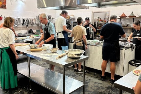 People cooking in a commercial kitchen, wearing aprons.