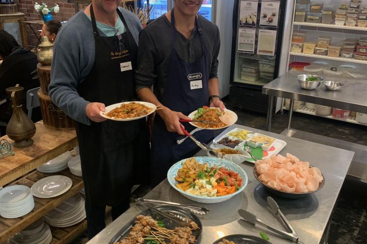 a group of people standing around a table with a plate of food