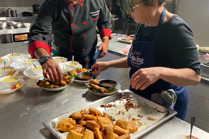 a group of people standing around a table with a plate of food