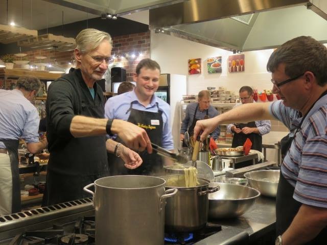 a group of people standing in a kitchen preparing food