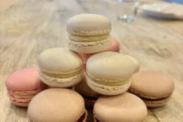 Assorted macarons stacked on a wooden table with blurred background.