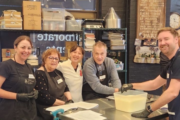 Five people smiling in a kitchen setting with baking supplies.