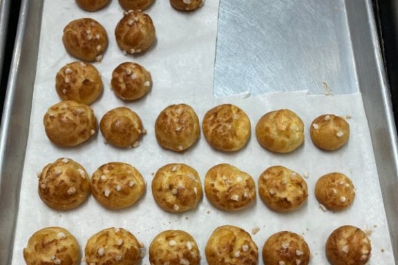 Tray with rows of round pastries topped with sugar on parchment paper.