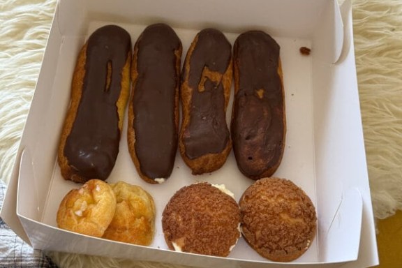 Box with three chocolate eclairs and two cream-filled pastries.