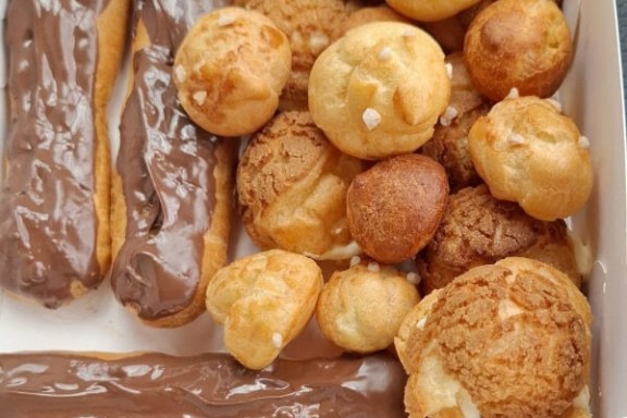 Box of chocolate eclairs and assorted cream puffs.
