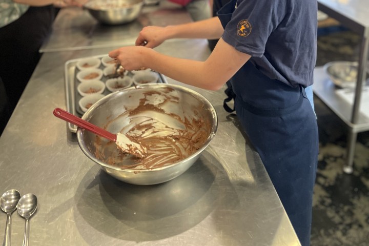 Person filling muffin cups with batter in a kitchen