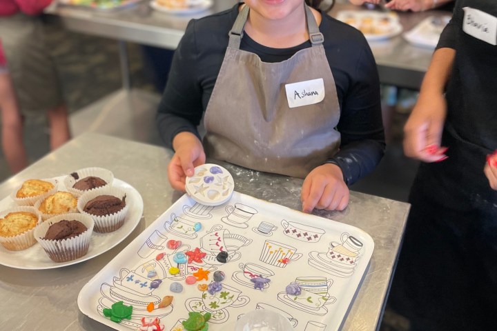 Child decorating cookies in a kitchen setting with others.