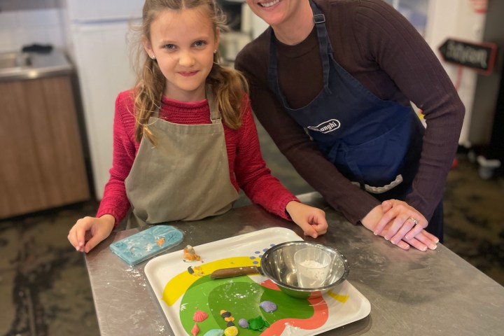 Woman and girl smiling in a kitchen with baked goods on a table.
