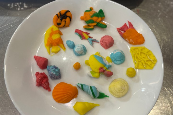 White plate with colorful, small clay figures and shapes on a metallic surface.