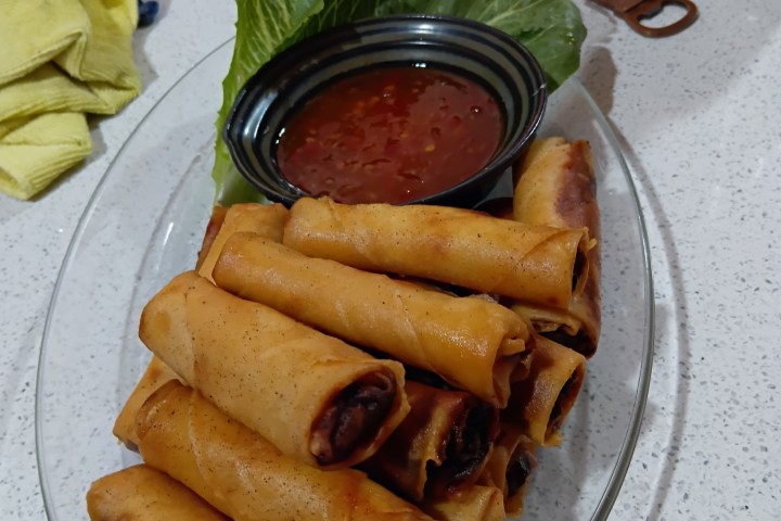 Plate of spring rolls with dipping sauce on lettuce.