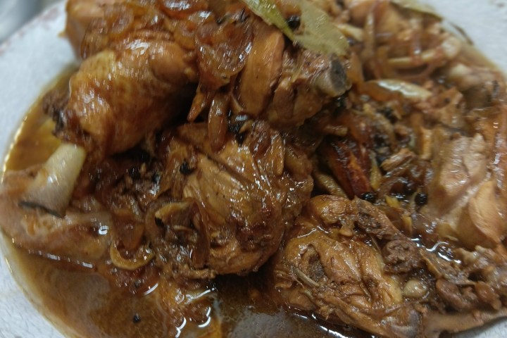 Plate of stewed chicken with spices and sauce.