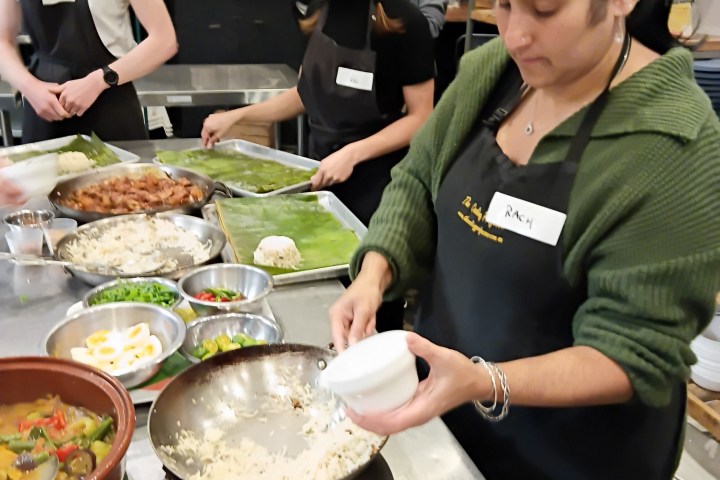 People cooking together in a kitchen with ingredients on a counter.