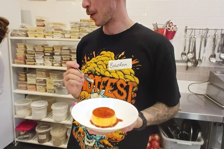 Person holding a dessert plate in a kitchen setting, wearing a T-shirt with the name tag.