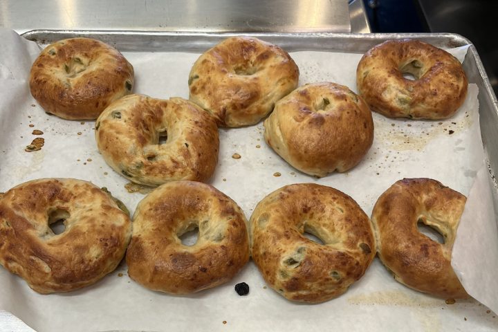 Nine baked bagels on a parchment-lined baking sheet.