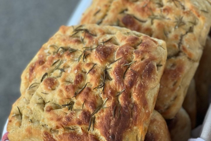 Loaves of rosemary focaccia bread on a red-striped cloth.
