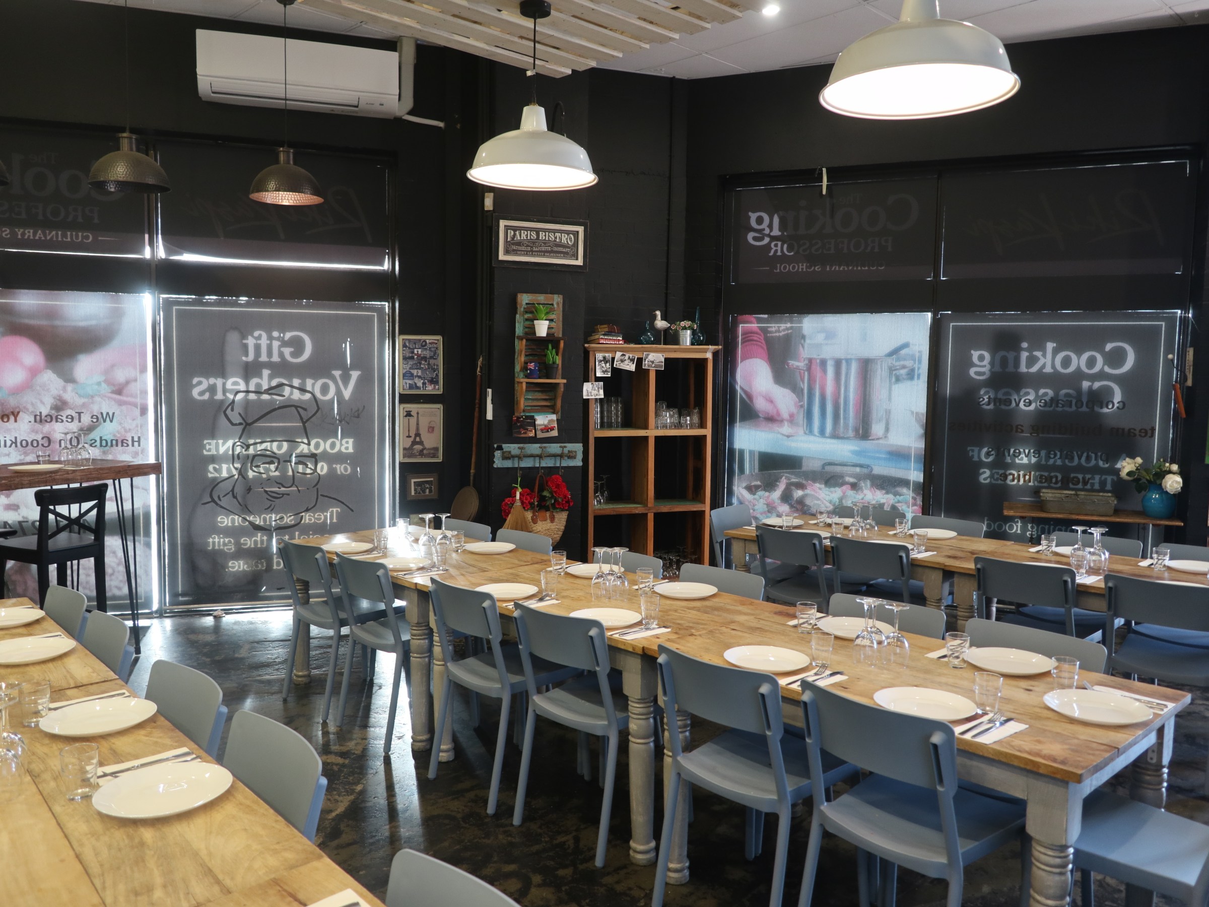 Tables set for a cooking class in a cozy, dimly-lit room with decorative elements.