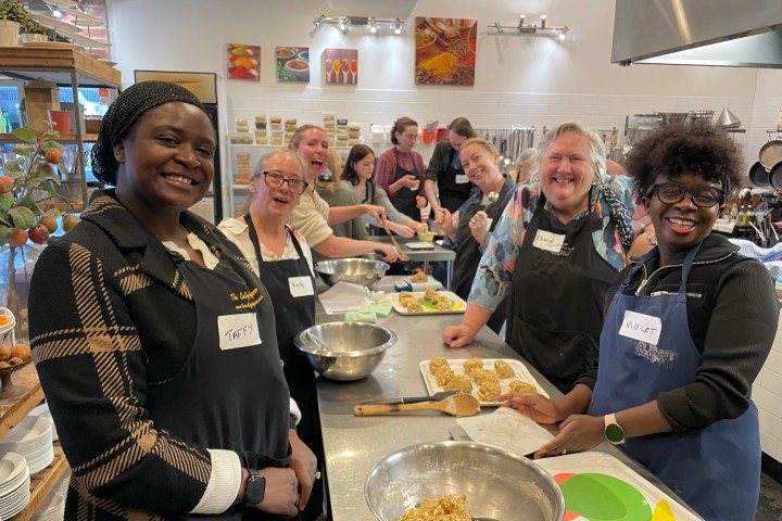 Group of diverse people cooking together in a kitchen, smiling and enjoying the activity.