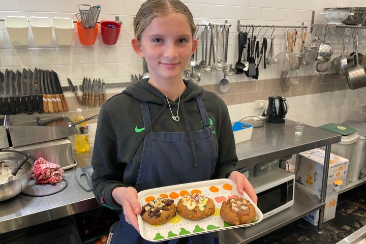 Person holding a tray with cookies in a kitchen.