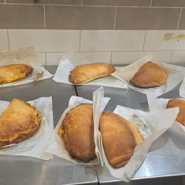 Assorted baked calzones on parchment paper in a kitchen.